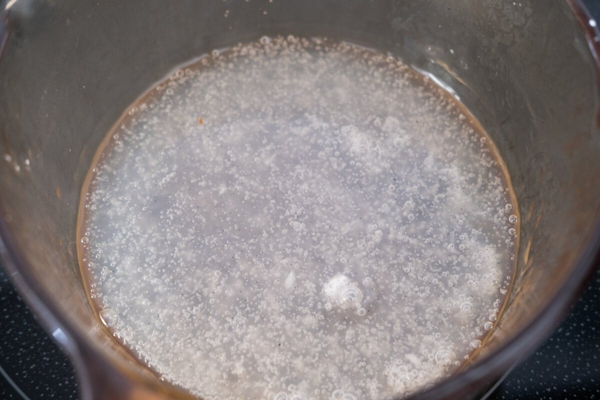Thick and clear combination of sugar, cornstarch, water and vanilla bean seeds in a saucepan. 