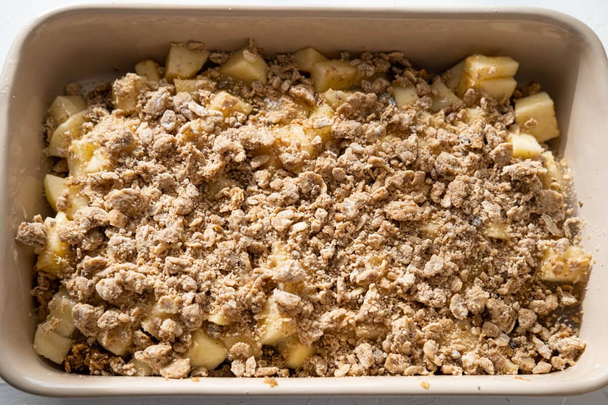 Flour mixture sprinkled on top of chopped apples in a baking tray. 