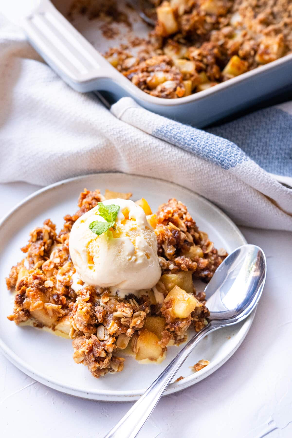 Apple crisp served with ice cream on top on a plate. 