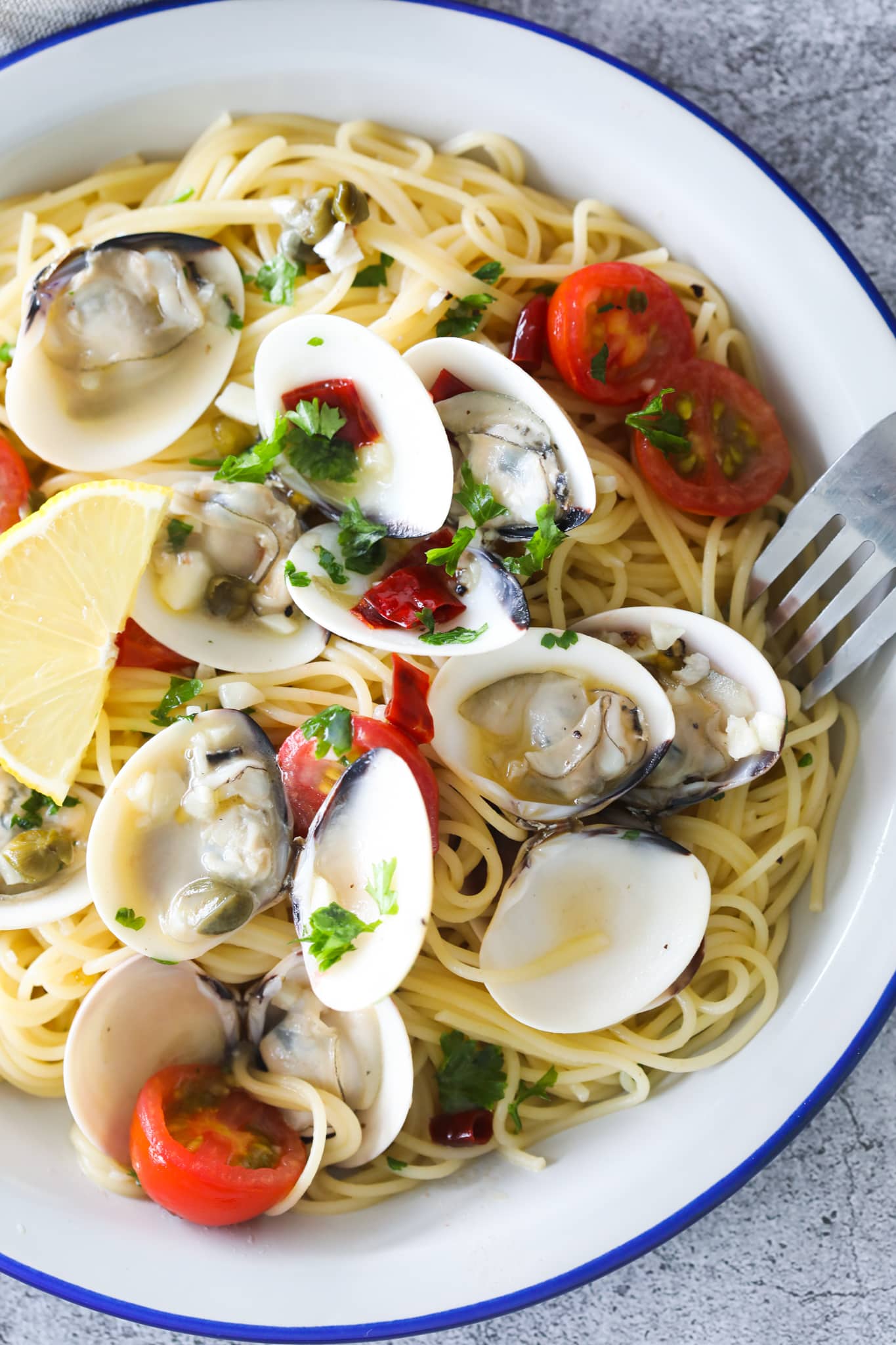 Capellini spaghetti with tomatoes and clams served in a plate.
