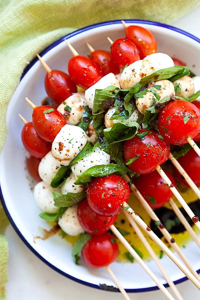 Caprese salad skewers, made with tomatoes, mozzarella, and basil leaves.