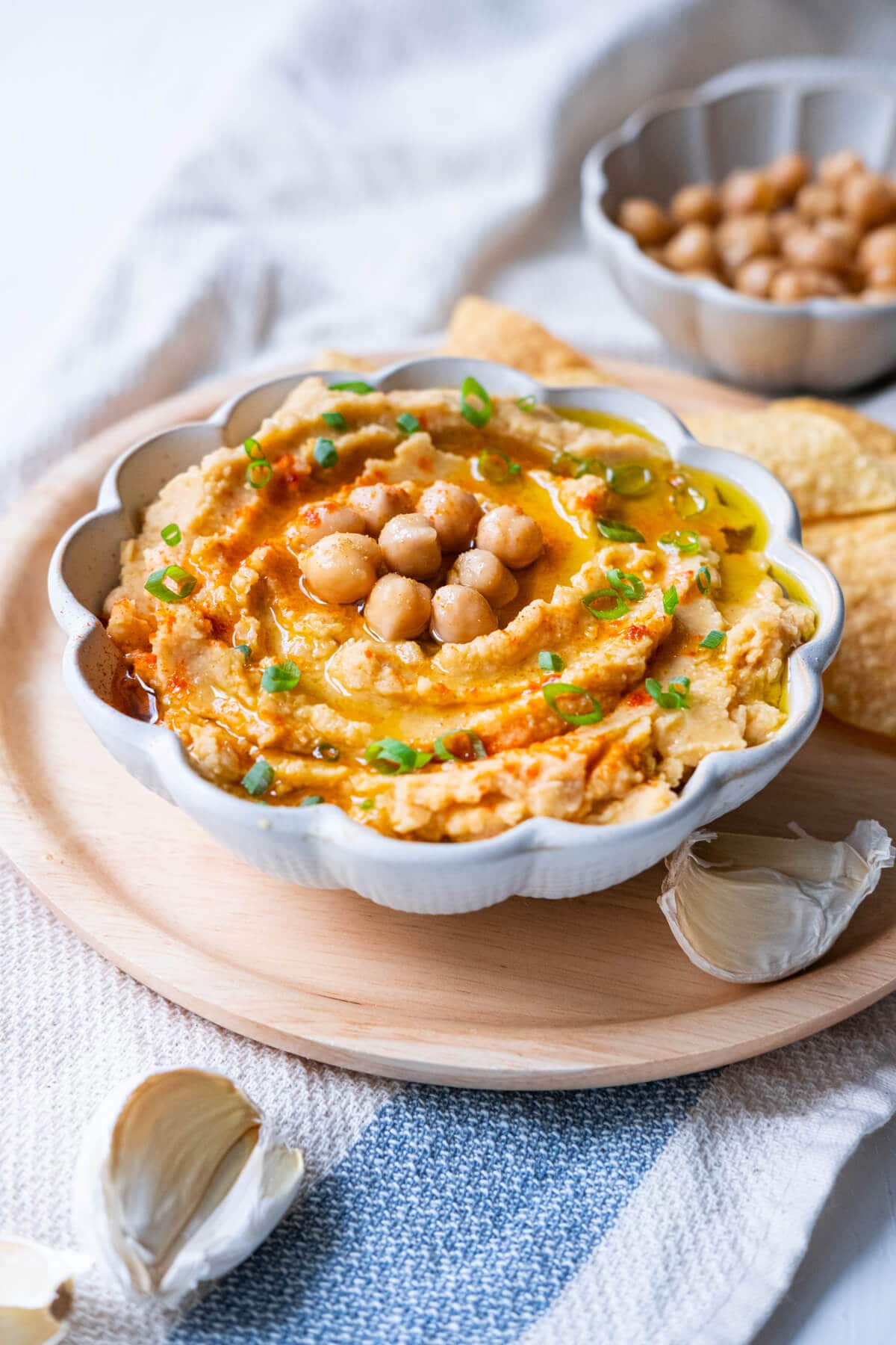 Delicious hummus served with chips, garlic, and more chickpeas on the side. 