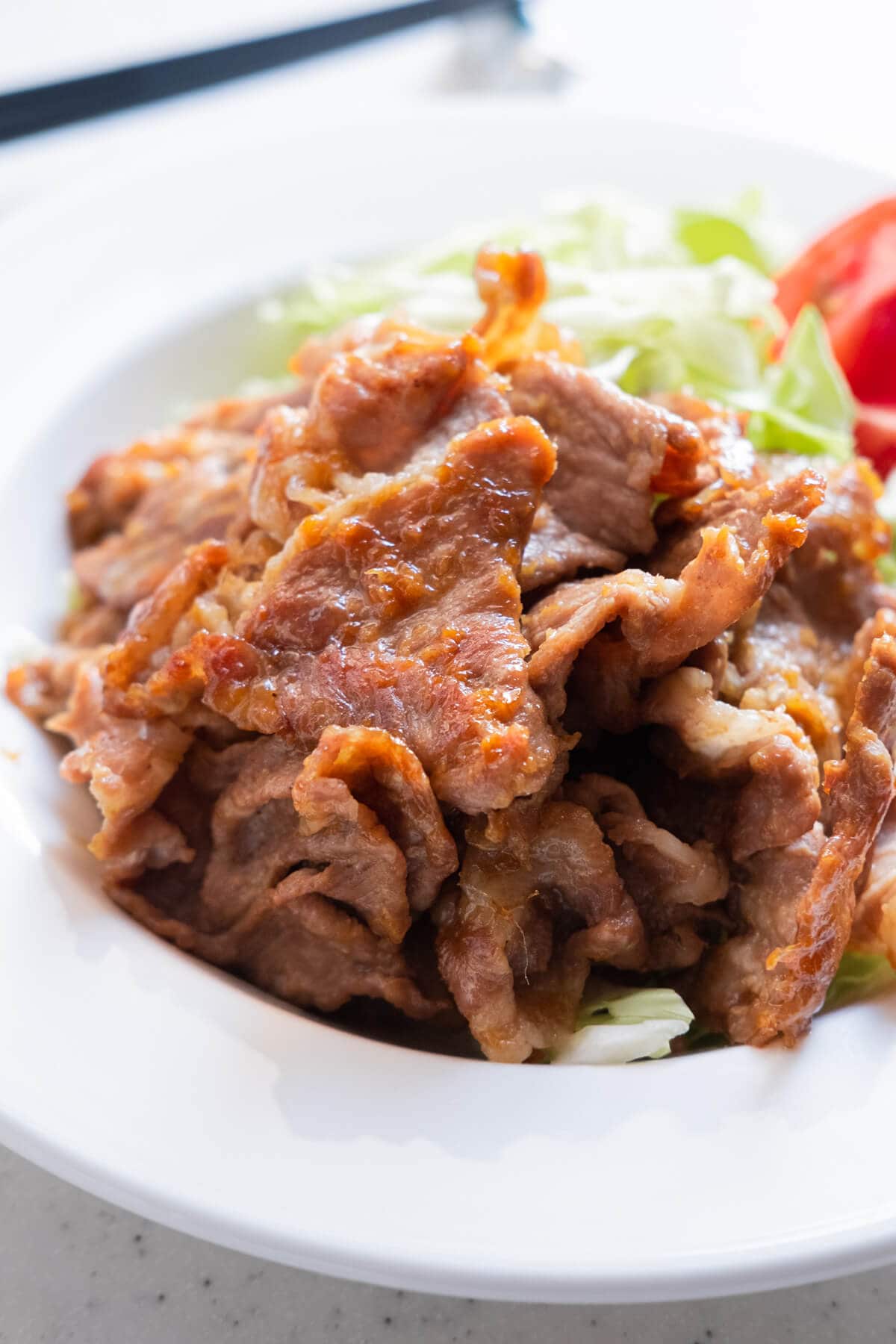 Tender, juicy pork slices coated with savory ginger sauce served in a plate.