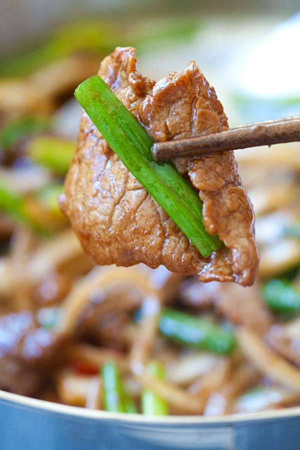 Homemade healthy Asian stir fry juicy beef picked with a pair of chopsticks.