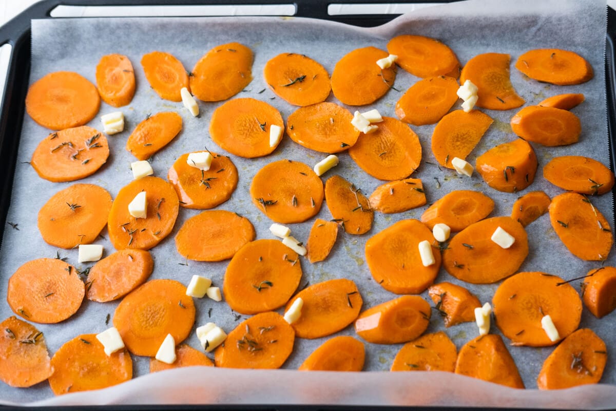 Carrot slices arranged on the baking pan lined with parchment paper and dot with butter. 