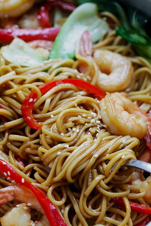 Closeup of the lo mein noodles with shrimp on a fork with some sesame seeds on it. Super saucy and delicious.
