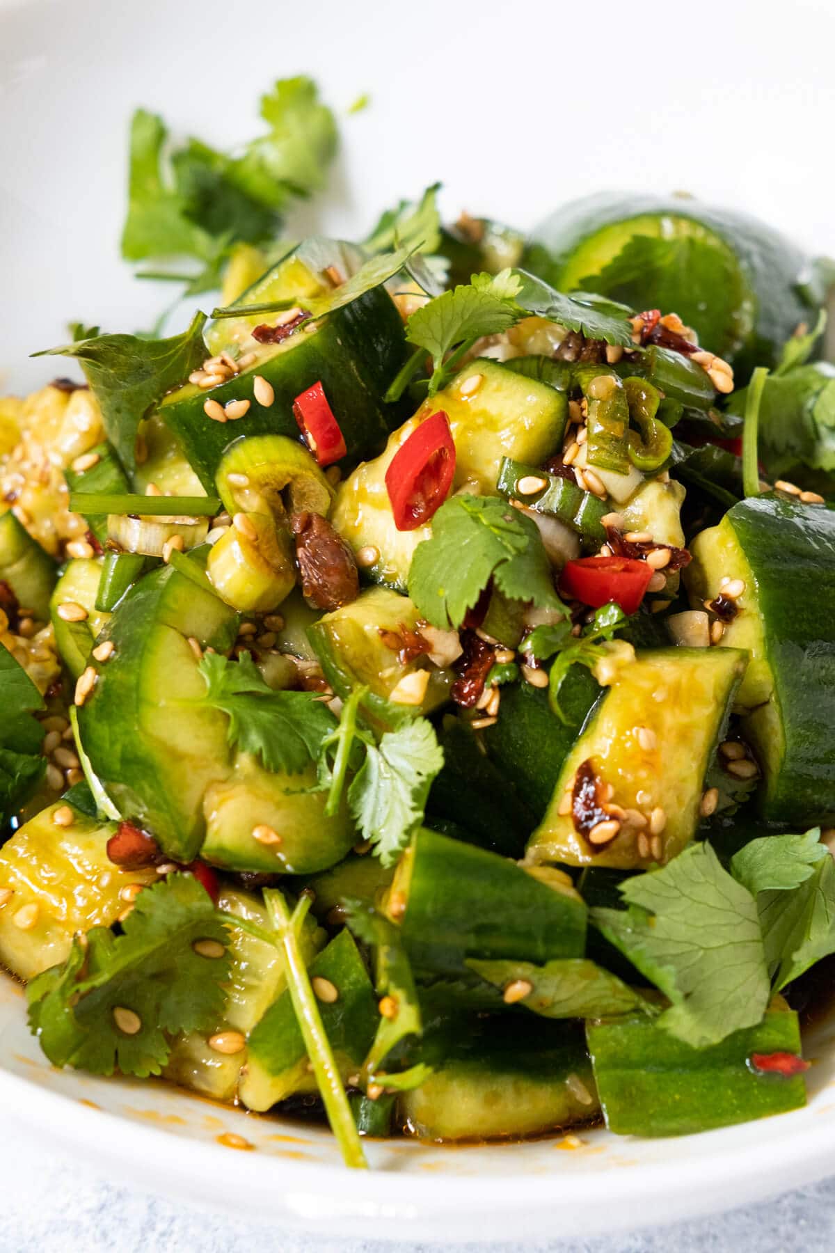 Crispy smashed cucumber tossed with a spicy and sour dressing and topped with chopped red pepper, spicy chili crisp, white sesame seeds and cilantro.  