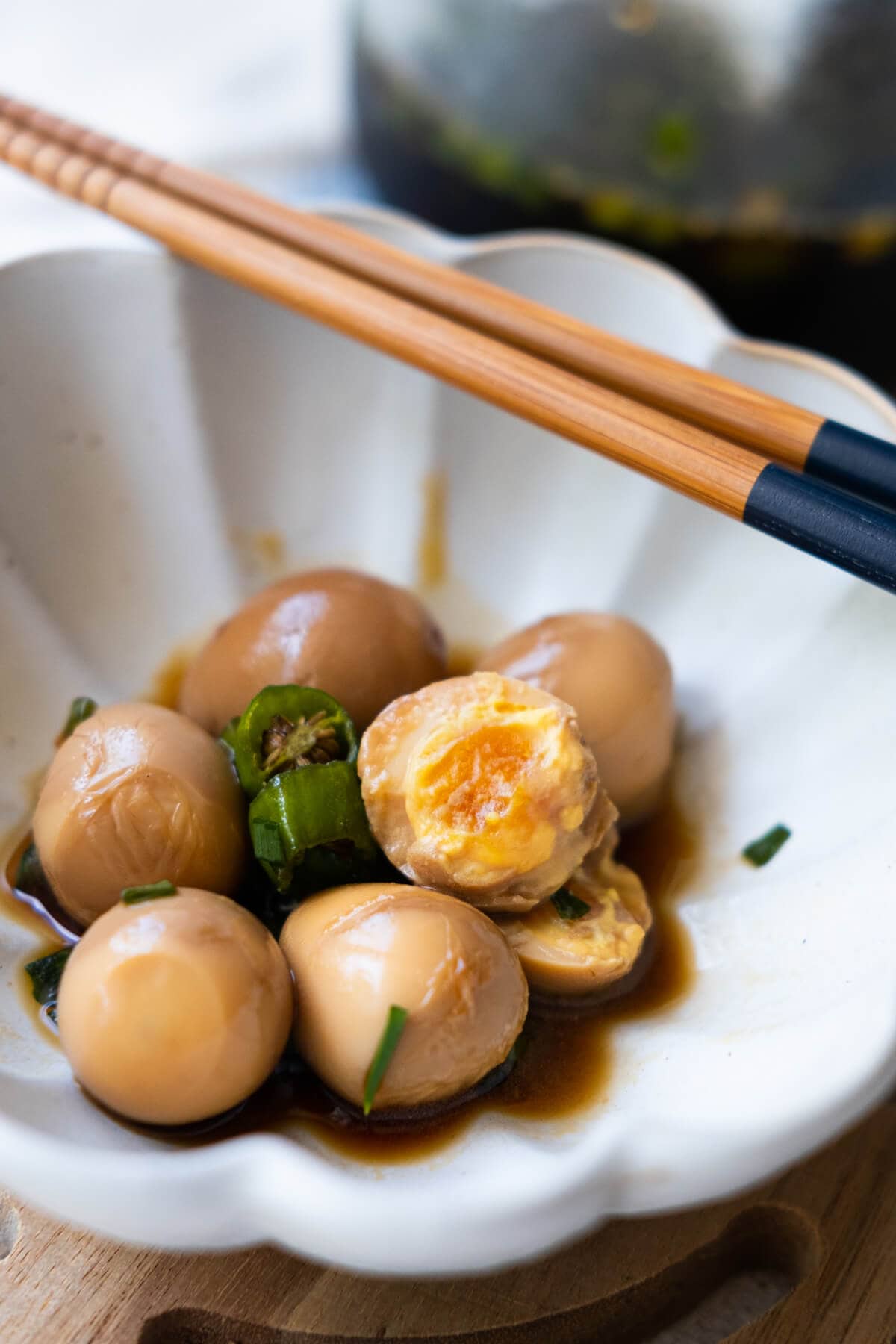 Soy sauce soaked brown quail eggs  with creamy egg yolk and chili pepper served in a bowl with chopsticks. 