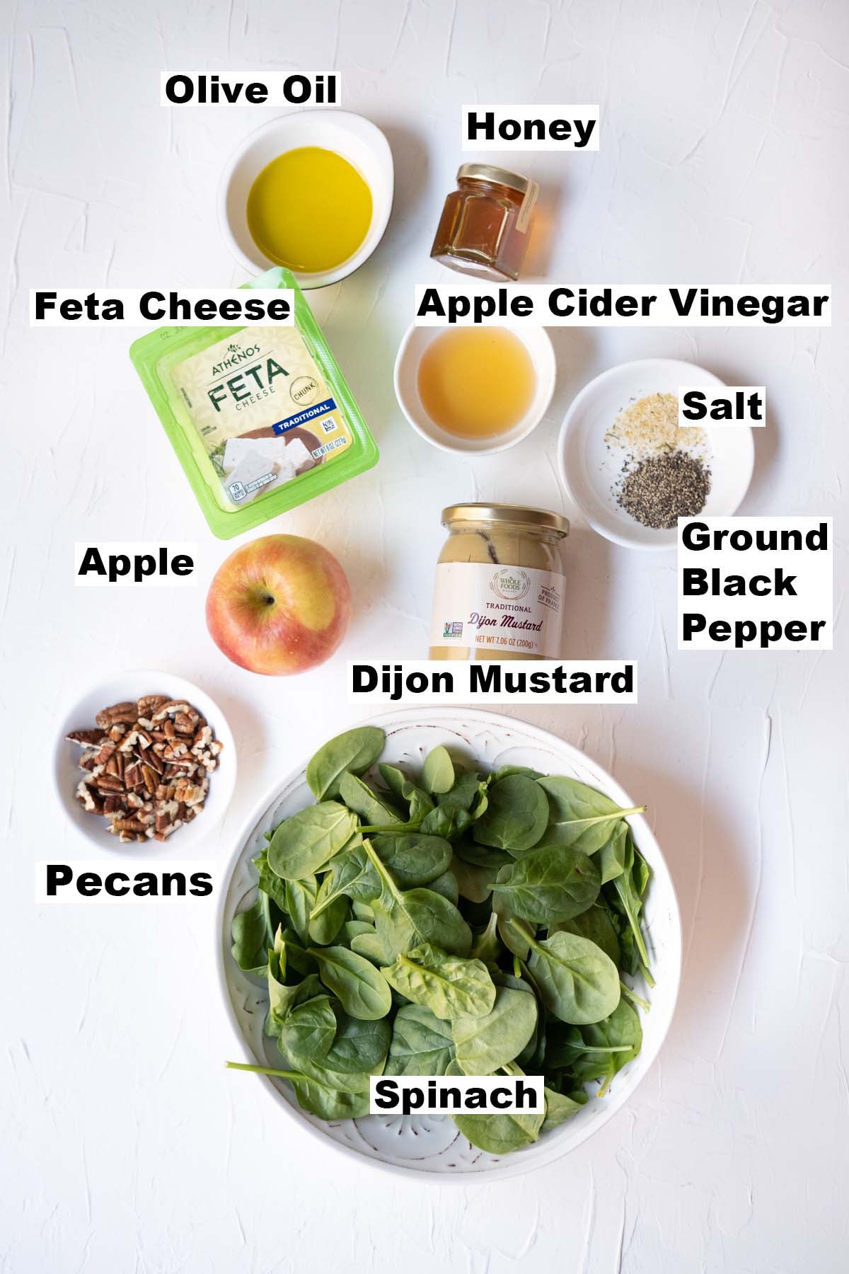 The picture shows the ingredients of spinach salad with apples, pecans and feta recipe. 