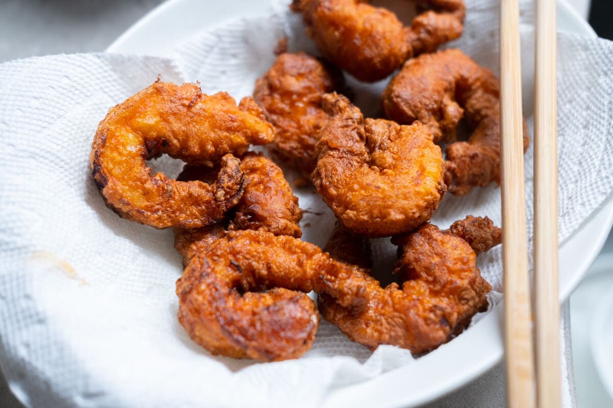 Deep-fried golden brown shrimps in a bowl lined with kitchen towel.