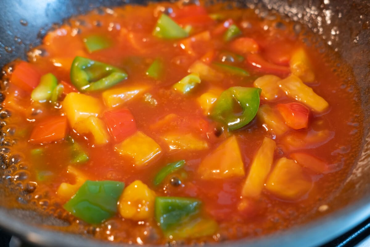 Sweet and sour sauce cooked with bell peppers and pineapples in a pan. 